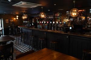a bar with bar stools and bottles of alcohol at Greyfriars Inn by Greene King Inns in St. Andrews