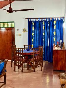 a dining room with blue curtains and a table and chairs at Dara Place in Dickwella