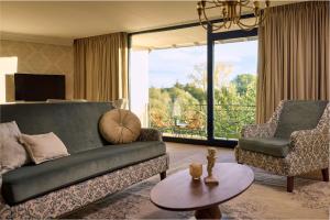 a living room with a couch and a chair and a table at Van der Valk Hotel Melle - Osnabrück in Melle