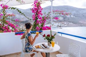 a woman sitting at a table with a glass of orange juice at Aegialis Hotel & Spa in Aegiali