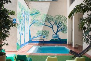 a swimming pool with a mural of trees on the wall at Ten To Go Hostel in Barcelona