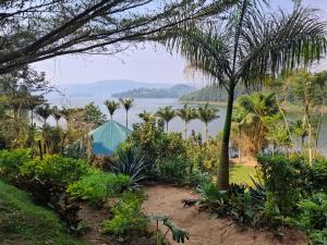 a garden with palm trees and a lake in the background at Paradise Resort in Chabahinga