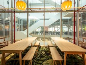a row of wooden tables in a building with windows at JO&JOE Vienna in Vienna