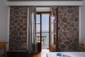 a bedroom with a door leading to a balcony at Olive Press Hotel in Mythimna