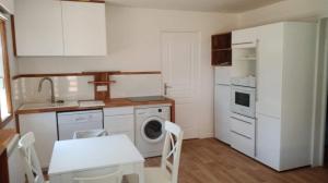 a kitchen with white appliances and a table and chairs at COSY T3 LACANAU in Lacanau +4 photos