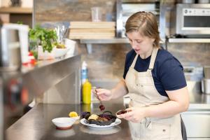 a woman in a kitchen preparing a plate of food at Kultur Weingut Kästenburg in Ratsch an der Weinstraße