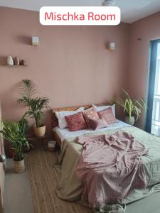 a bedroom with a bed with pink walls and potted plants at Blue Door Homes in Navi Mumbai