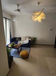 a living room with a blue couch and a table at Blue Door Homes in Navi Mumbai