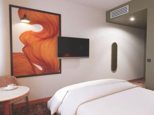 a bedroom with a bed and a tv on the wall at All Suites Hôtel Chartres Centre Gare in Chartres