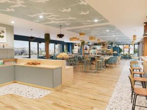 a restaurant with a counter and chairs and tables at All Suites Hôtel Chartres Centre Gare in Chartres