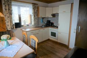 a kitchen with white cabinets and a table with a tableablish at Ferienhaus Kammerer in Haidberg +13 photos