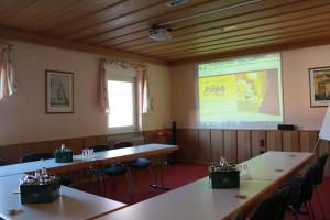 Sala de conferencias con mesas y pantalla de proyección en Hotel-Restaurant Fröhlich, en Kaiserslautern