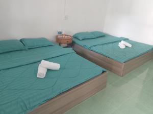 two beds in a bedroom with green sheets and towels at Hom Ba cây dừa in Vĩnh Hy