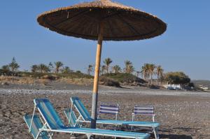 two lounge chairs and an umbrella on a beach at Villa Imerti Kiotari in Kiotari