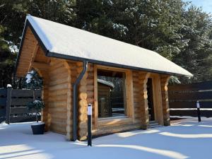 a log cabin with a roof in the snow at Balujemy w Radawie in Radawa