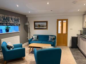 a living room with a blue couch and chairs at 8 Crickhowell Cottages, Standard St, Central Crickhowell in Crickhowell