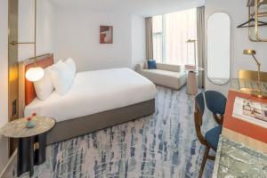 a hotel room with a bed and a chair and a table at Dorsett Hotel Canary Wharf in London