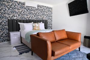 a bedroom with a bed and a leather couch at His Grace Eagles Guesthouse in Bloemfontein
