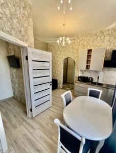a white table and chairs in a kitchen with a table and cabinets at Апартаменти Карабінерная 14 in Kropyvnytskyi