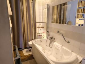a white bath tub in a bathroom with a sink at Maison Romane 1136 in Cluny