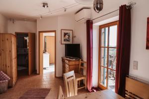 a living room with a table and a tv and a window at Kultur Weingut Kästenburg in Ratsch an der Weinstraße