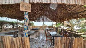 a restaurant with tables and chairs and a straw roof at Happy Corner Beach Garden in How Ba