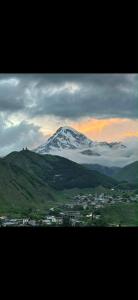 a snow covered mountain with a town in front of it at Zaga Cottage in Kazbegi