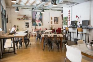 a restaurant with tables and chairs and a person sitting at a counter at Ten To Go Hostel in Barcelona