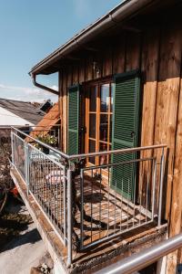 a wooden house with green doors and a balcony at Kultur Weingut Kästenburg in Ratsch an der Weinstraße