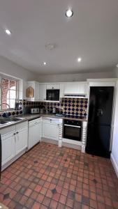 a kitchen with white cabinets and a black refrigerator at The Coach House WPH, Epping in Epping