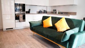 a green couch with two yellow pillows in a kitchen at Beautiful Flat 2-Mins away from Rochester Station in Rochester