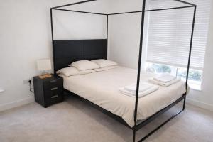 a bedroom with a black canopy bed with white sheets at Beautiful Flat 2-Mins away from Rochester Station in Rochester