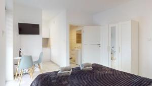 a white bedroom with a bed and a table at Studio Fibra Lungo in Rybnik