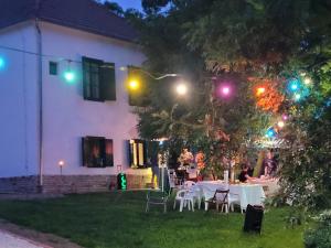 a house with tables and chairs in the yard at night at VILLABOGArT Esküvő-és Rendezvényhelyszín in Alsobogát