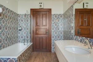 a bathroom with a tub and a sink and a door at Pousada Castelo de Palmela in Palmela +26 photos