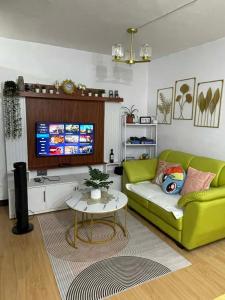 ein Wohnzimmer mit einer grünen Couch und einem Fernseher in der Unterkunft Chyns Suite in Marilao