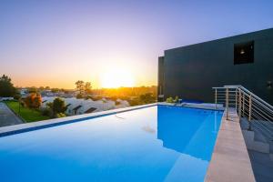 a swimming pool in front of a building with the sunset at Luxury Apartment Unit 111 Le Jardin in George