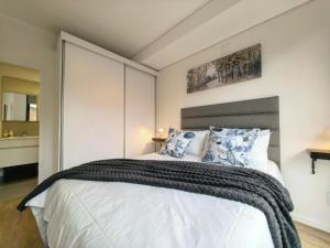 a bedroom with a large white bed with blue pillows at Luxury Apartment Unit 111 Le Jardin in George +8 photos