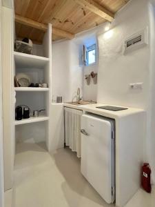 a white kitchen with a refrigerator and a sink at Lythi Kythnos in Kithnos +17 photos