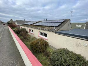 a house with solar panels on top of it at Hopeman Cottage in Hopeman