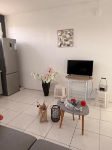 a living room with a table and a tv at Charmant T2 sur le robert in Le Robert