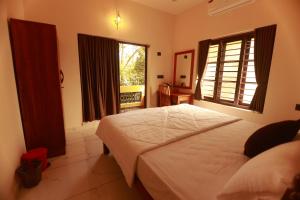 a bedroom with a large white bed and a window at Coastal Calm Inn in Fort Kochi
