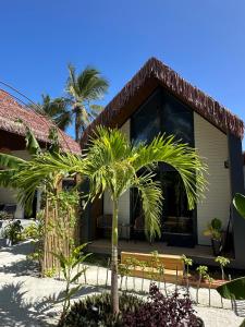 a house with a palm tree in front of it at Ambra Maldives in Thoddoo