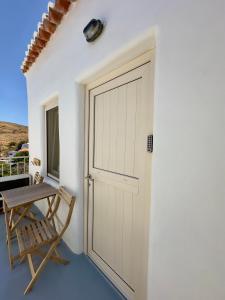 a door to a house with a table and a chair at Lythi Kythnos in Kithnos