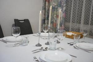 a table with wine glasses and plates and candles at HANOSAN Apartments Familienhaus 4 Zimmer 125 m2 in Garbsen
