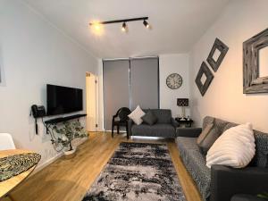 a living room with a couch and a tv at Luxury Apartment Unit 111 Le Jardin in George