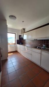 a kitchen with white cabinets and a tile floor at Gästehaus FaRitz in Knittelfeld