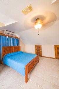 Un dormitorio con una cama y un ventilador de techo. en Casa Brisa Guest House, en San Pedro