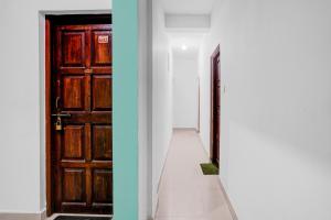a hallway with a wooden door and a white wall at Hotel O Kunal guest house in Goa