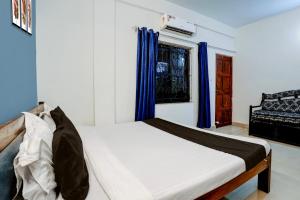 a bedroom with a bed with blue curtains at Hotel O Kunal guest house in Goa